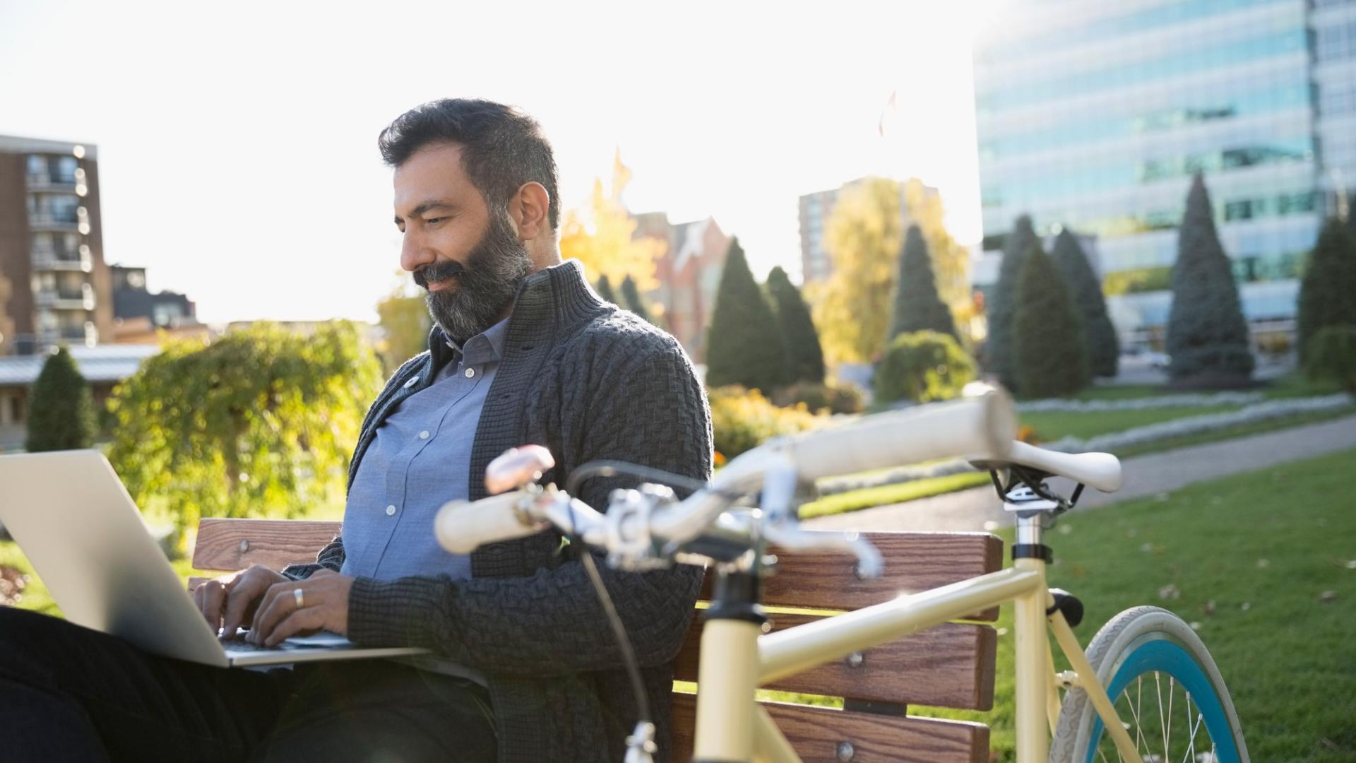 Ein Mann im Park mit Fahrrad und Laptop