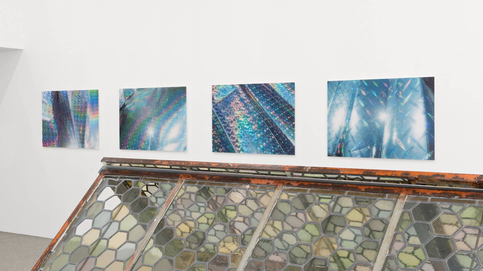 Vier grossformatige Fotos zeigen Nahaufnahmen von silbrigen Isolationsmatten, die regenbogenfarbig schimmern.