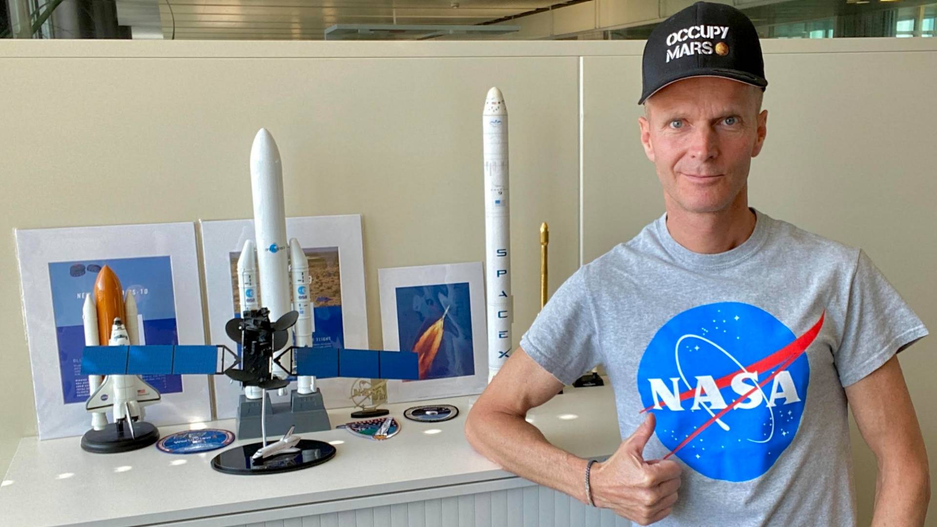 Man in NASA T-shirt standing next to an office cabinet