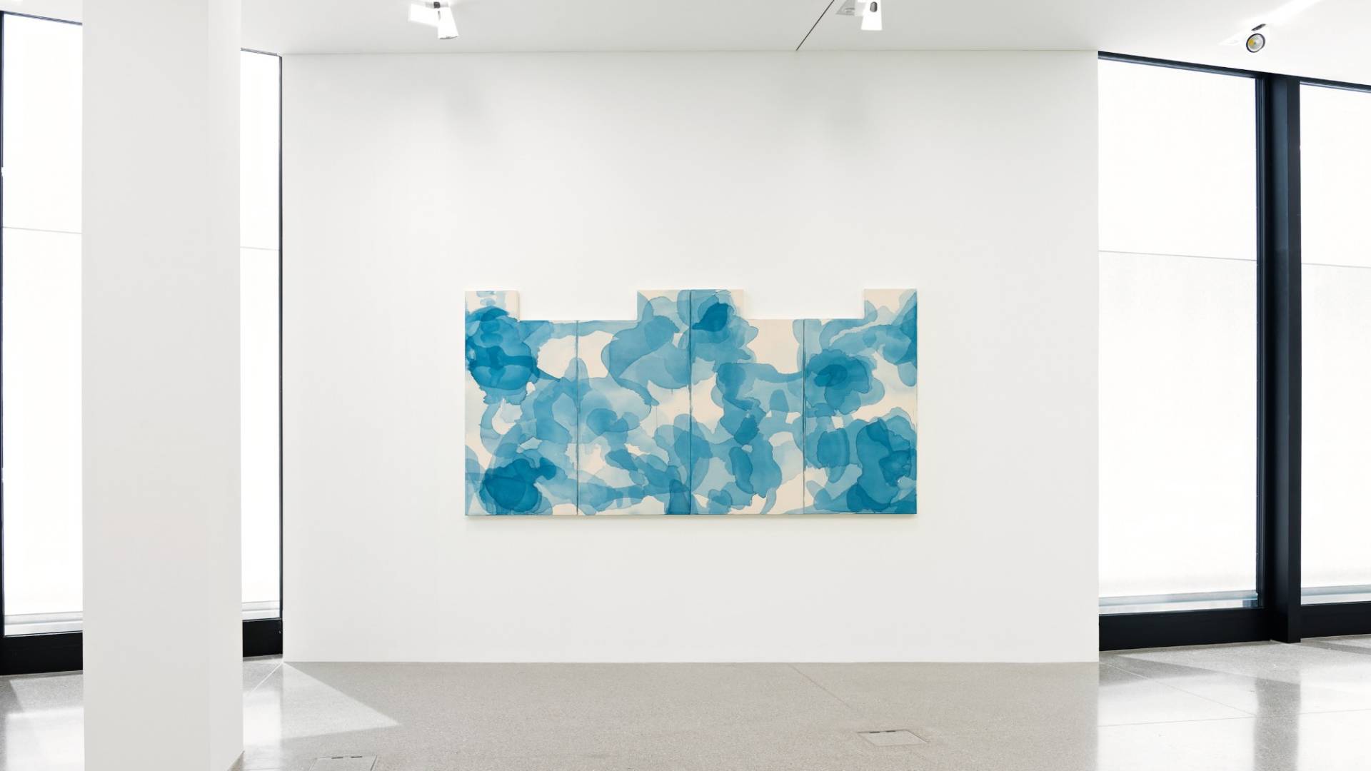 Delicate, cloud-like shapes in blue Chinese ink cover a row of four white canvases.