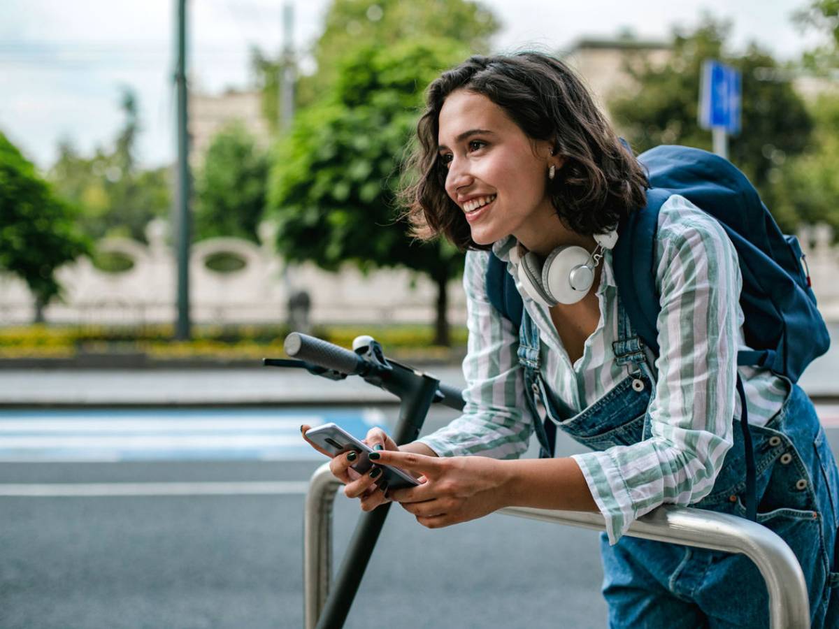 A woman on her mobile phone stops her e-scooter.