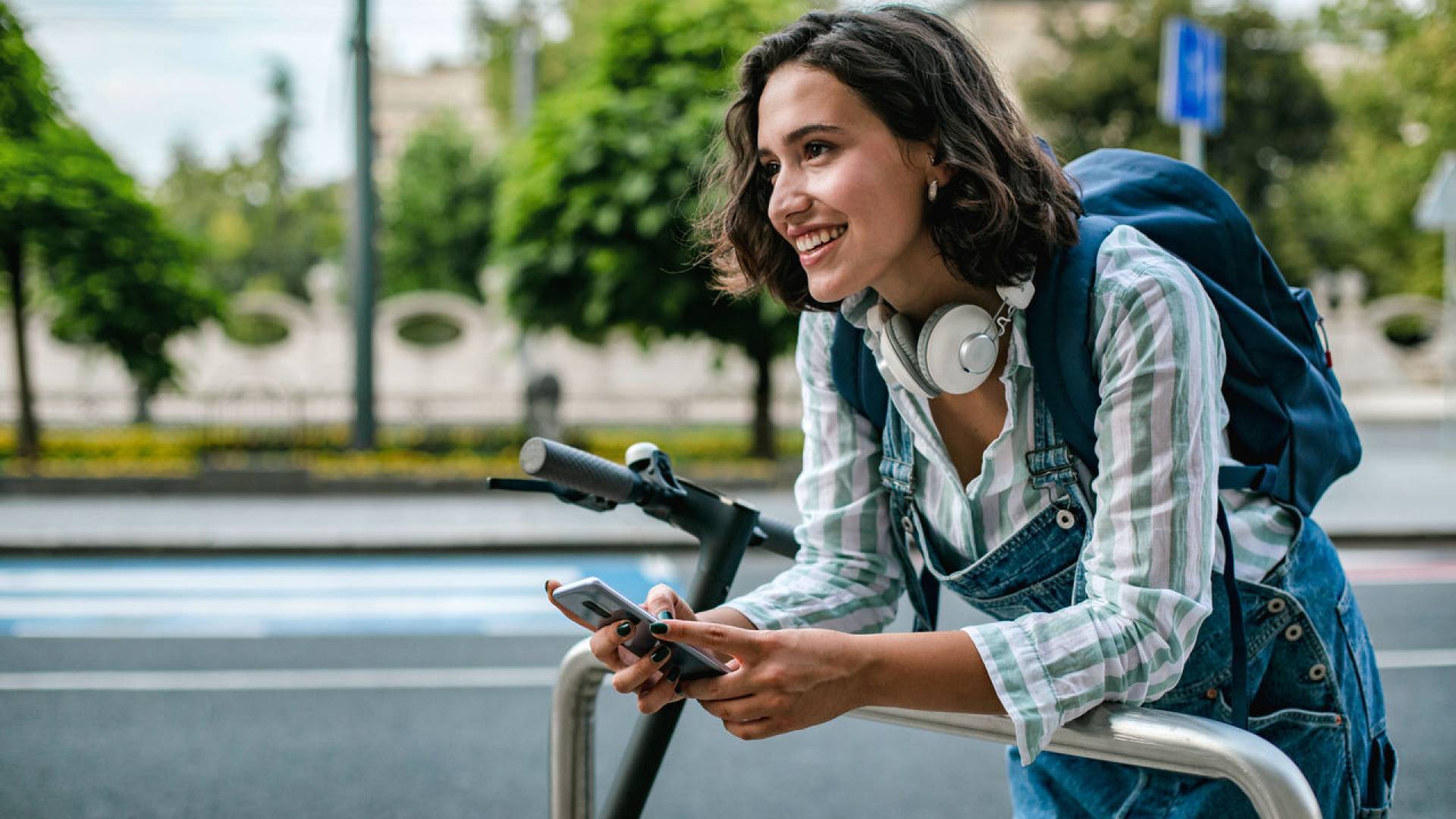 A woman on her mobile phone stops her e-scooter.