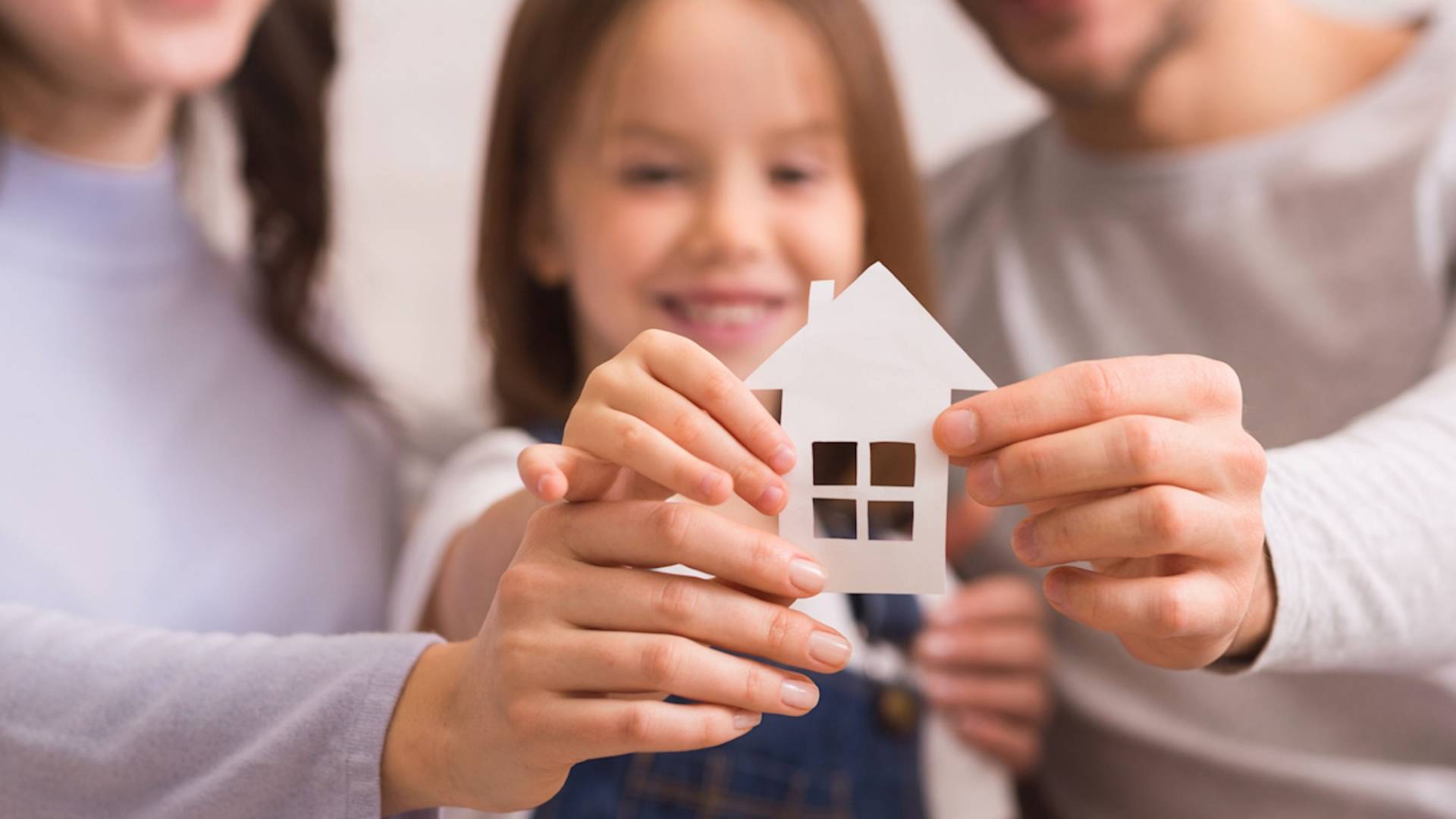 Family holding a paper cut-out of a small house.