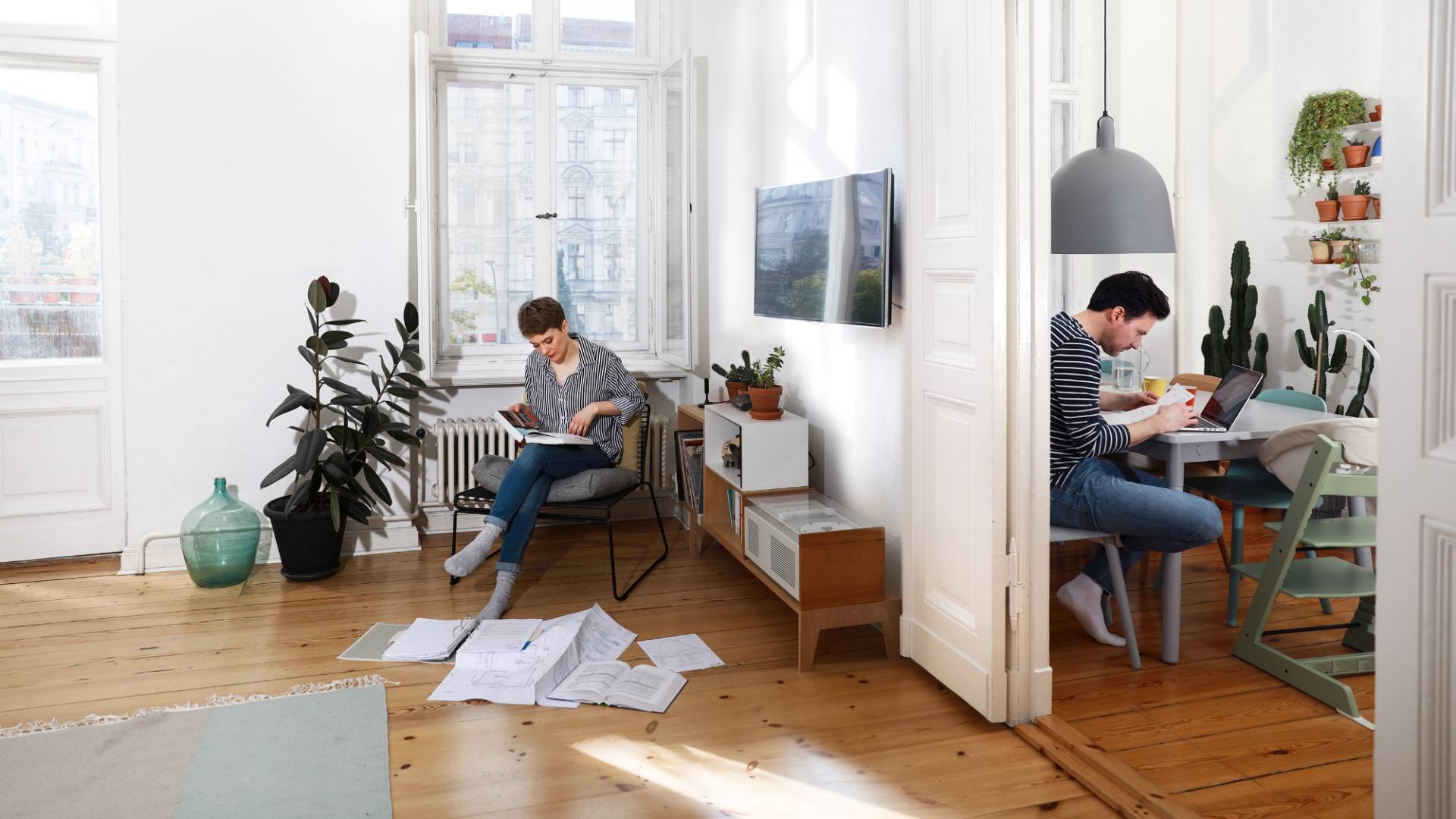Two people sit in an apartment and deal with documents.