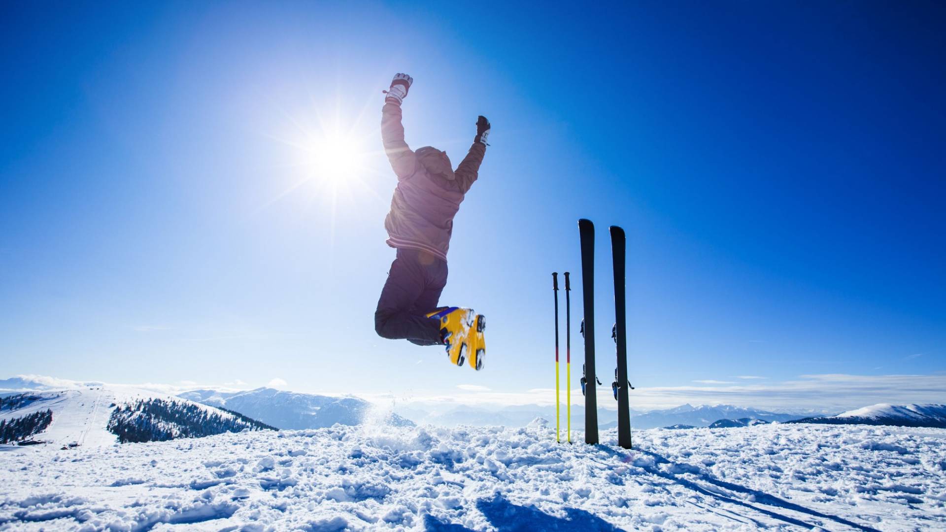 A skiier leaps into the air. Blue sky in the background and snow on the ground.
