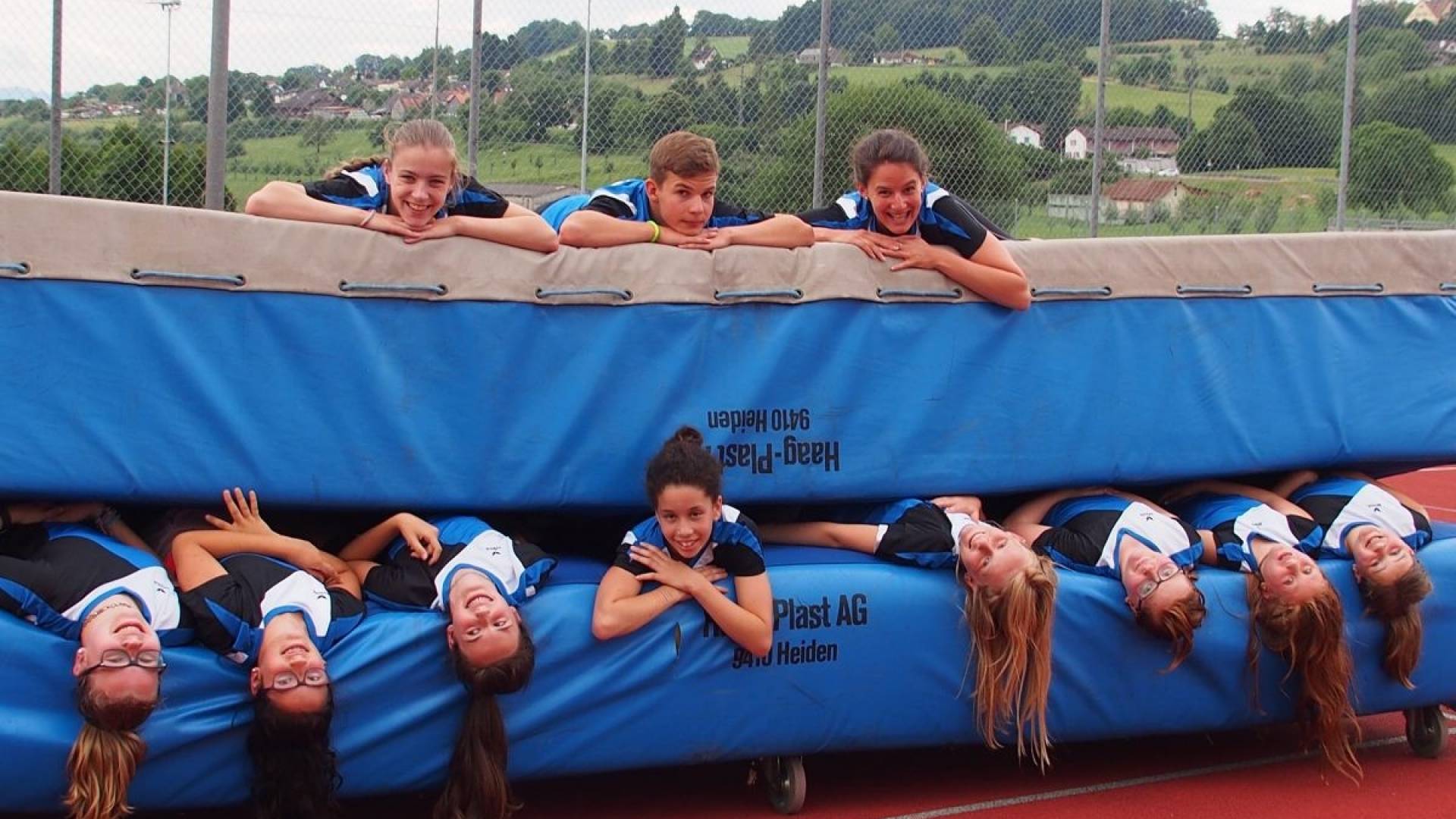 Des filles du club de gymnastique sont allongées sur de grands tapis d’entraînement.