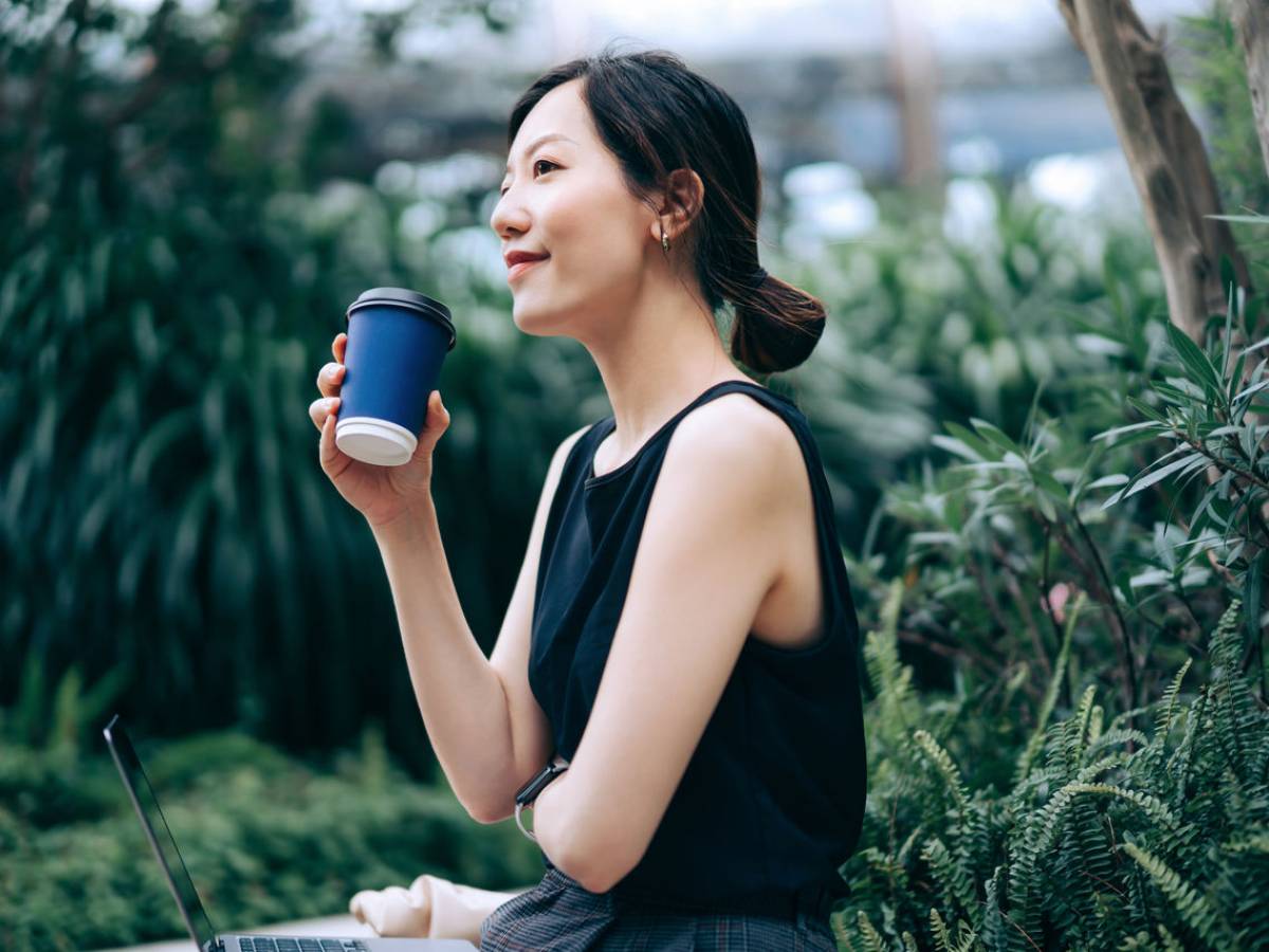 Une femme, une tasse de café à la main, se tient dans la serre.