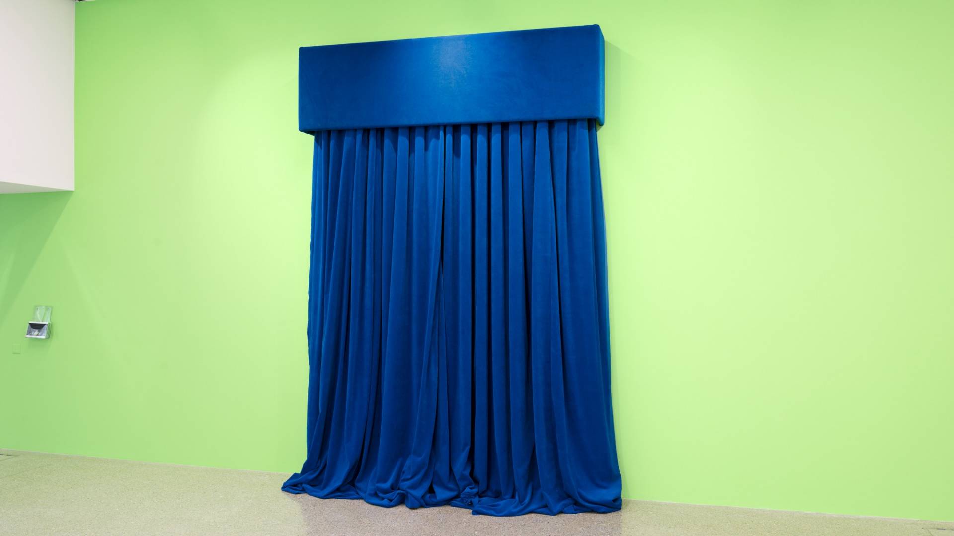 Rideau de velours bleu épais devant une paroi peinte en vert.