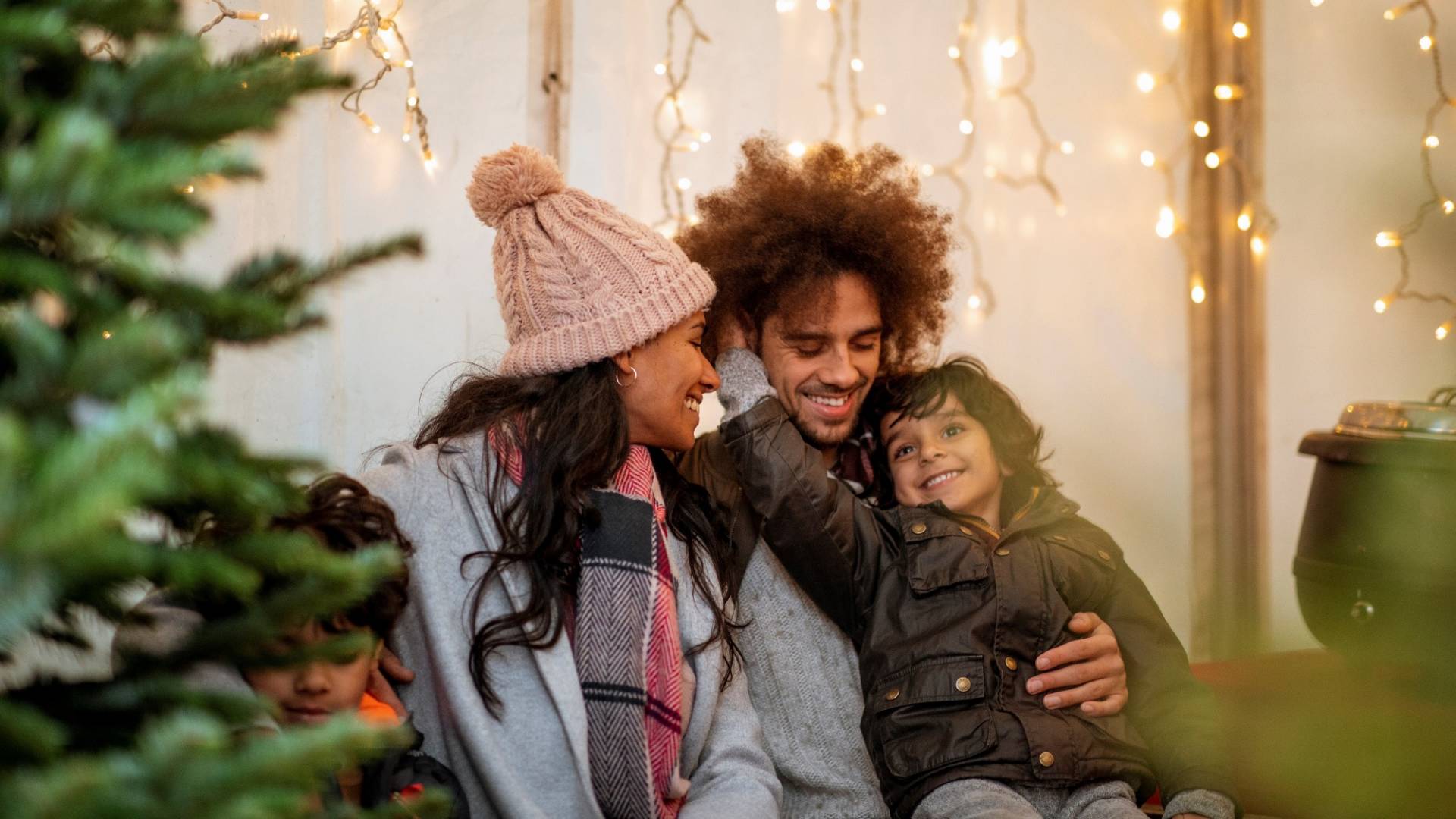Père, mère et enfant décorent ensemble l'arbre de Noël.