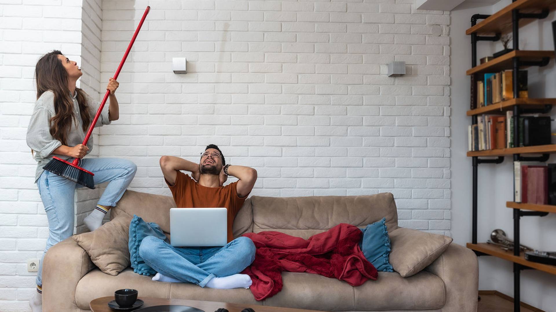 Young couple stares at the ceiling and yells because a neighbor upstairs is having a party with loud music or renovating an apartment and workers are drilling with heavy tools. Noise pollution concept