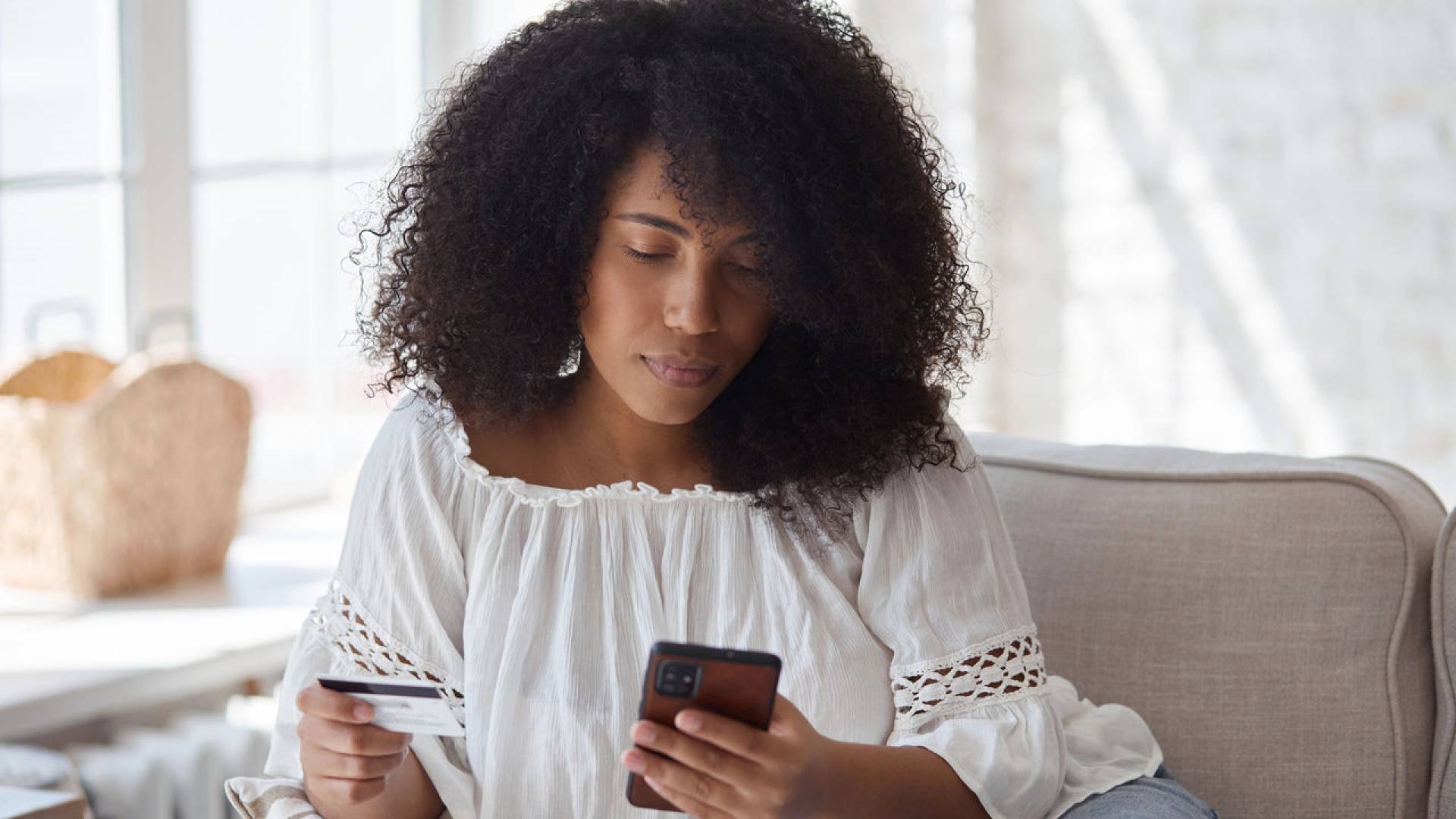 Young black woman spending money in internet websites and stores and making online payments.