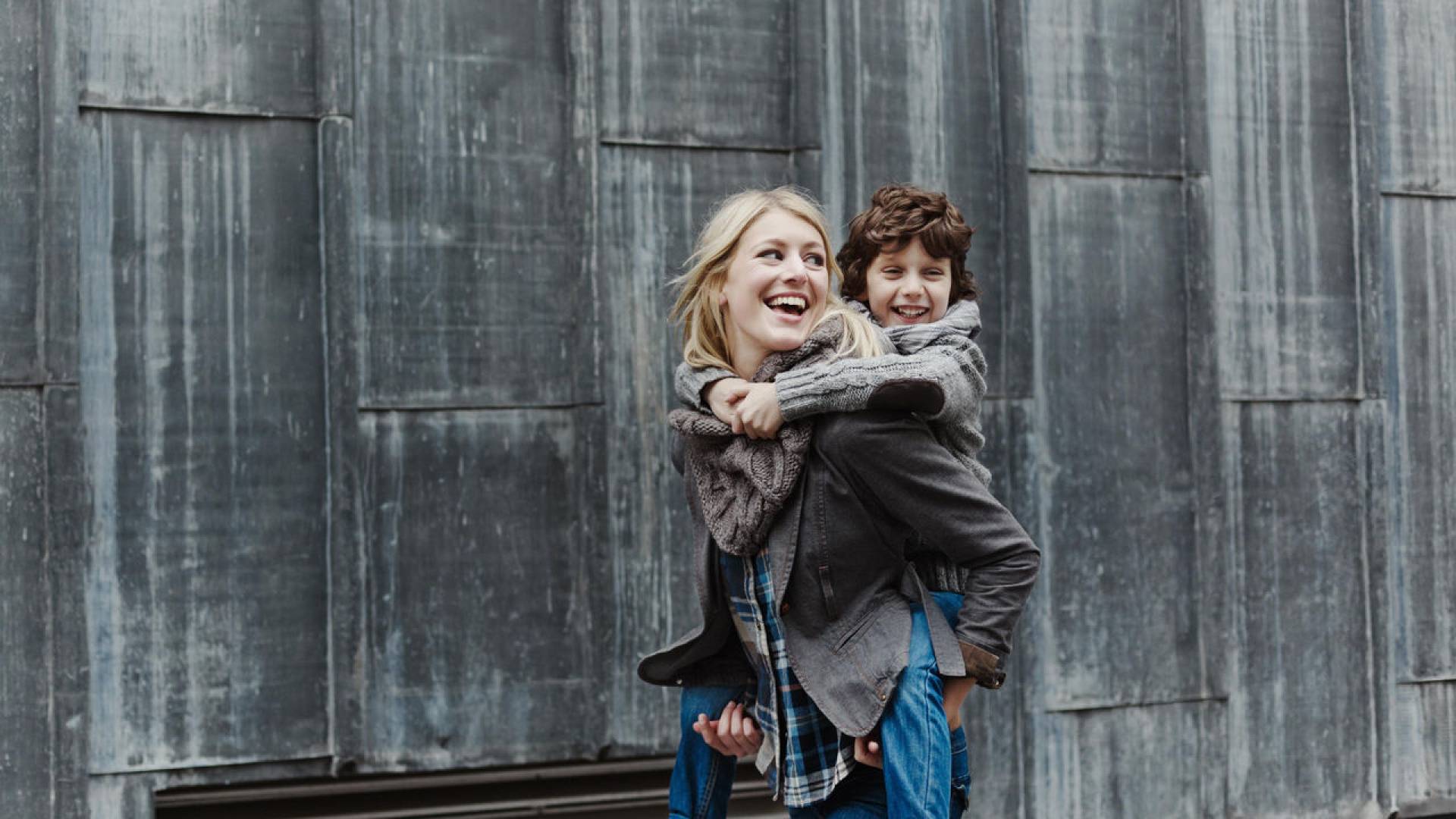 glueckliche-mutter-nimmt-sohn-huckepack
