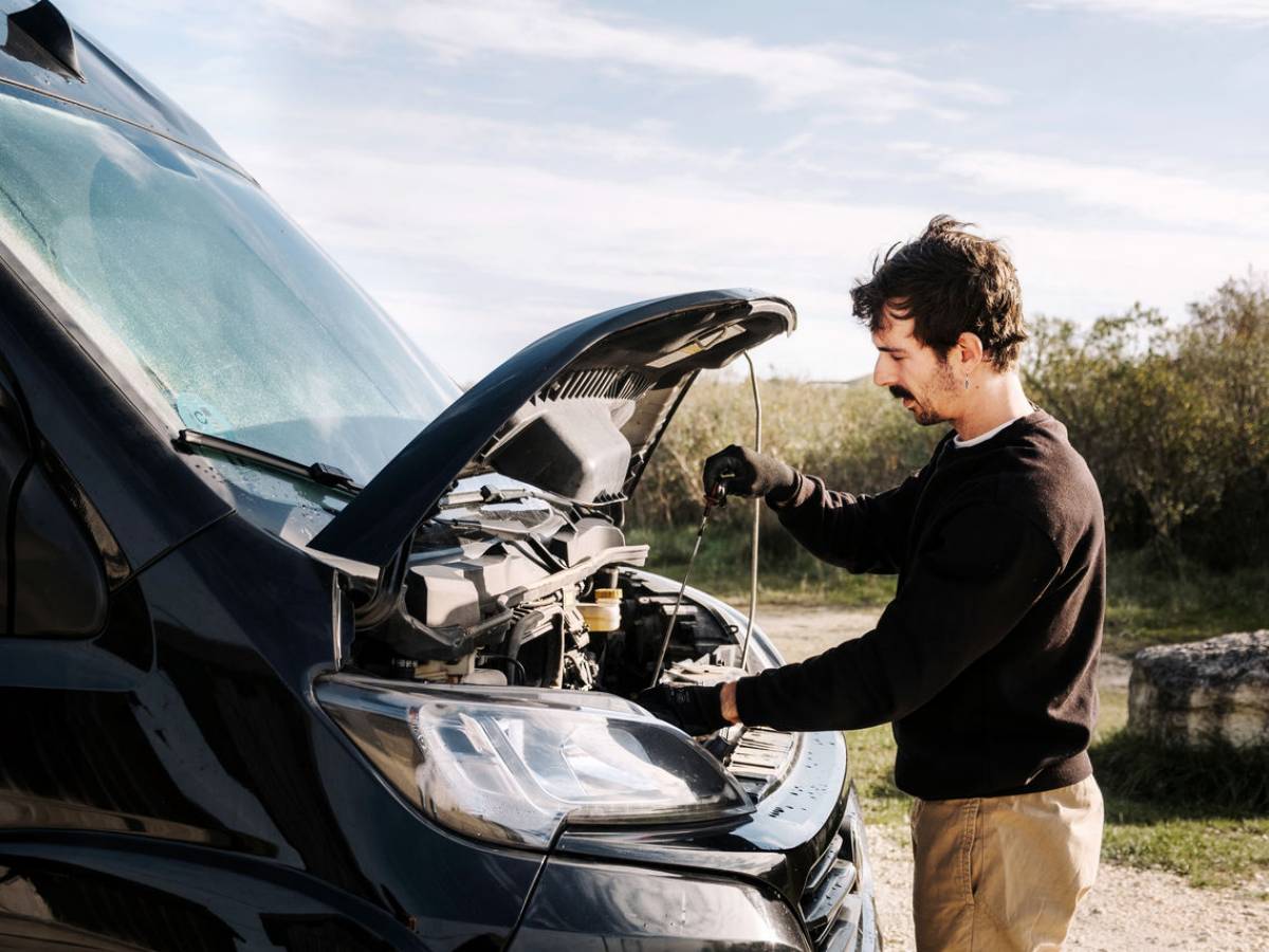 Un uomo con l'auto in panne in mezzo alla natura.