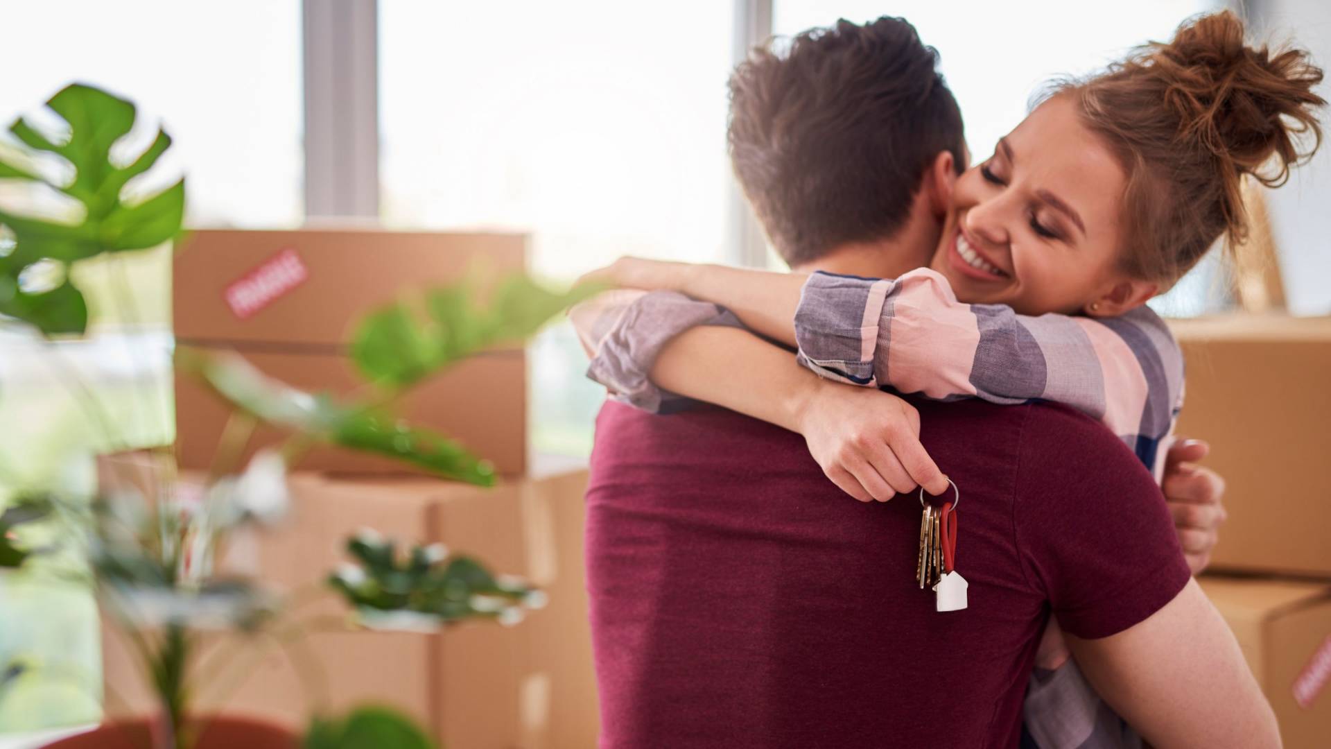 Una giovane coppia si abbraccia nell’appartamento in cui si è appena trasferita.