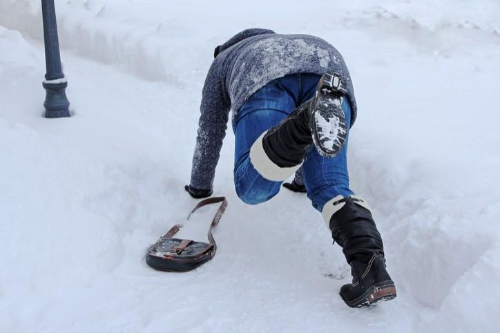 Eine Frau rutscht auf einem verschneiten Weg aus