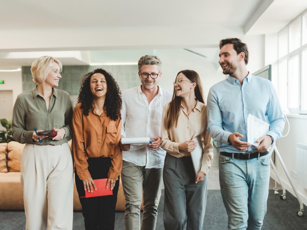 Mehrere lächelnde Personen im Casual-Business-Dress laufen nebeneinander.
