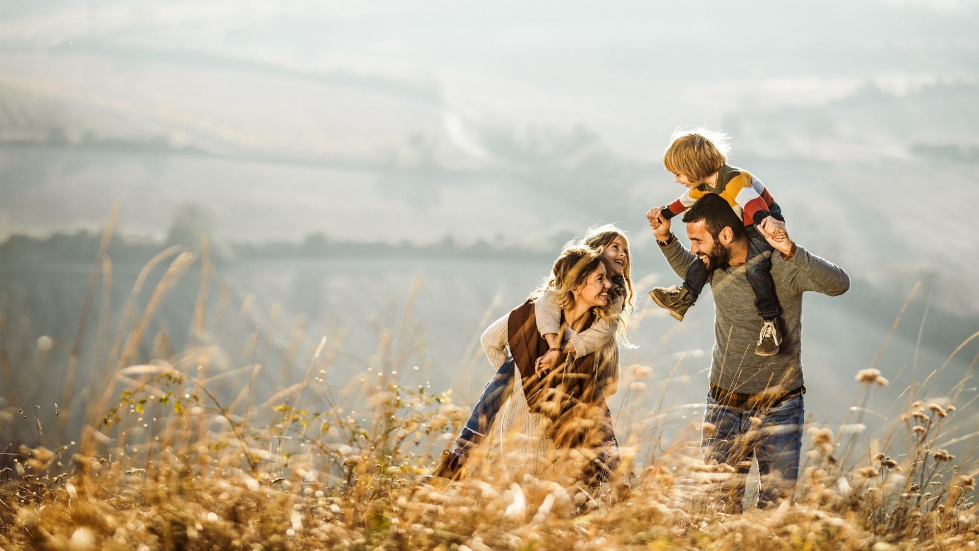 Eine glückliche Familie läuft durch ein Feld und genießt die Zeit mit ihren zwei Kindern.
