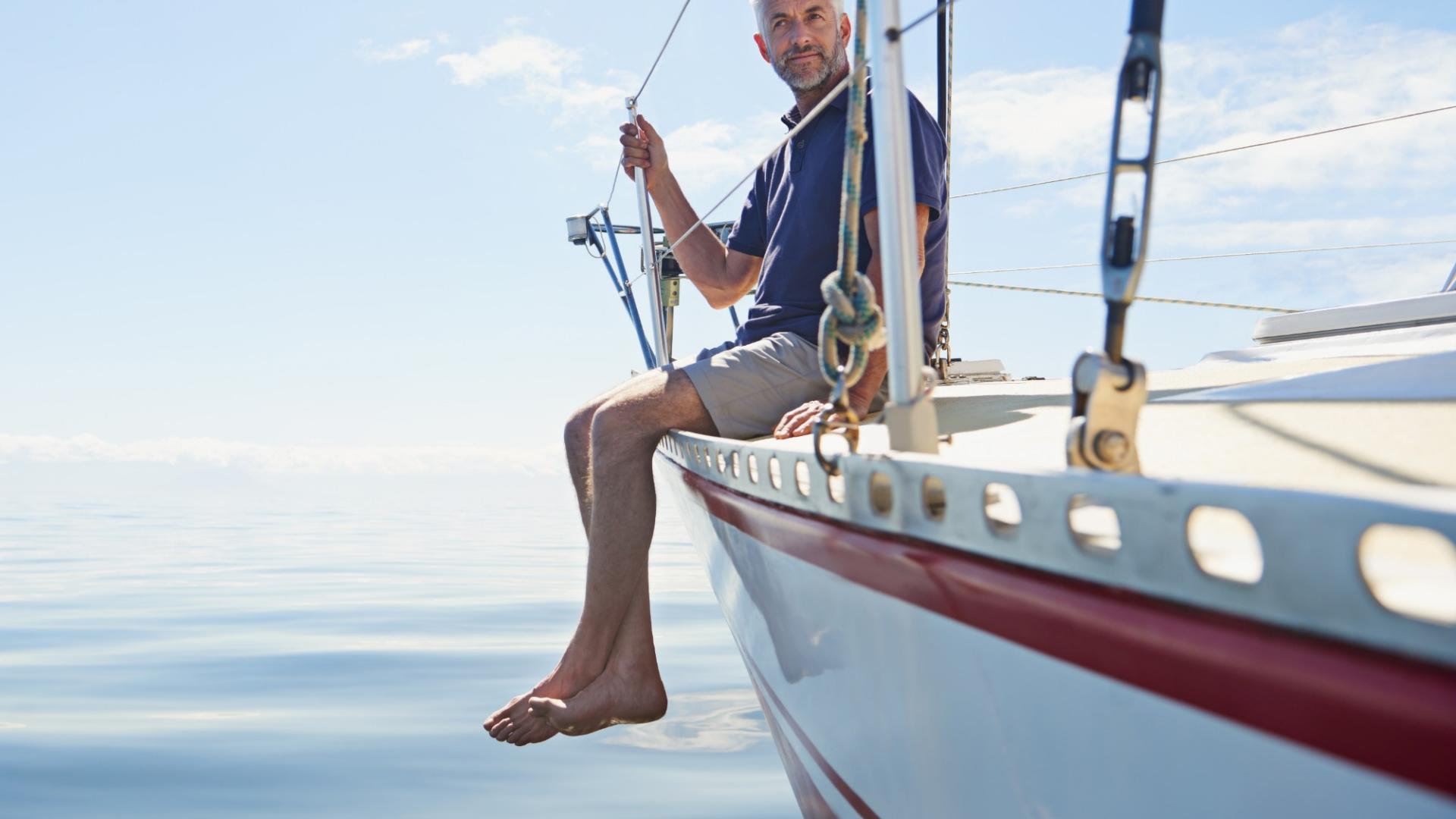 Ein Mann sitzt an Bord seiner Segeljacht auf dem Meer