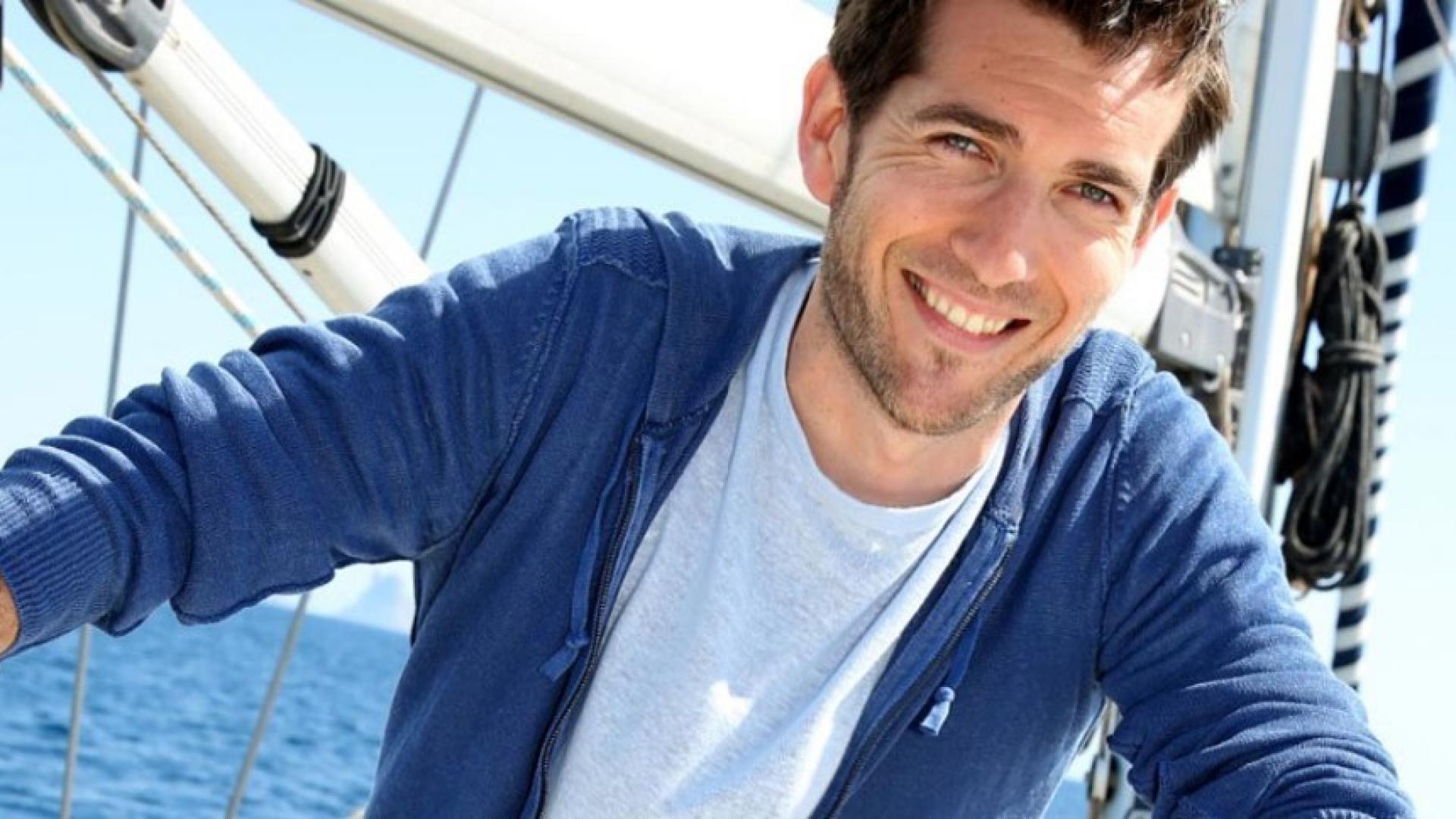 Ein Mann sitzt an Bord seiner Segeljacht auf dem Meer