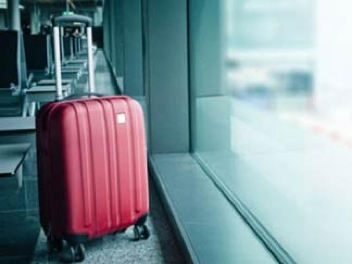 Roter Koffer vor Fenster am Flughafen | Helvetia Versicherungen