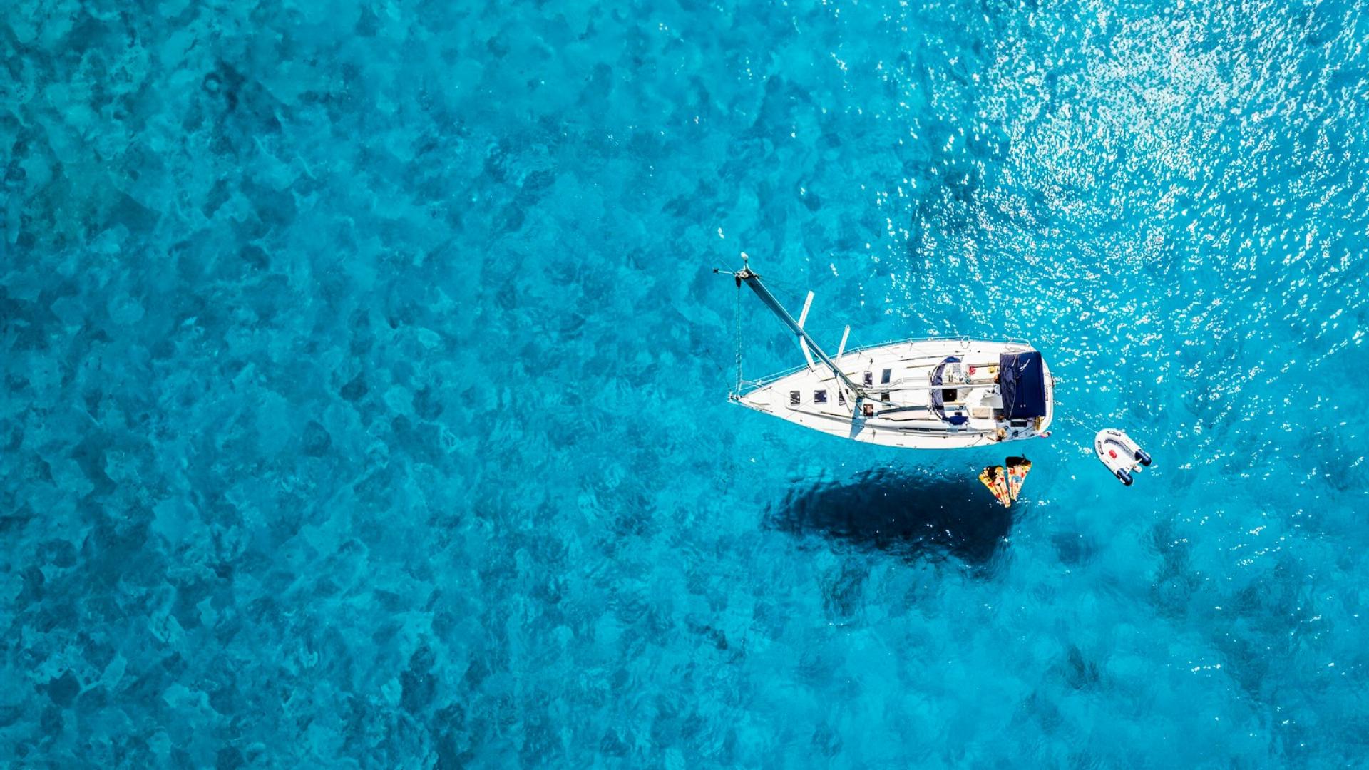 Ein Segelboot liegt auf türkisblauem Wasser.