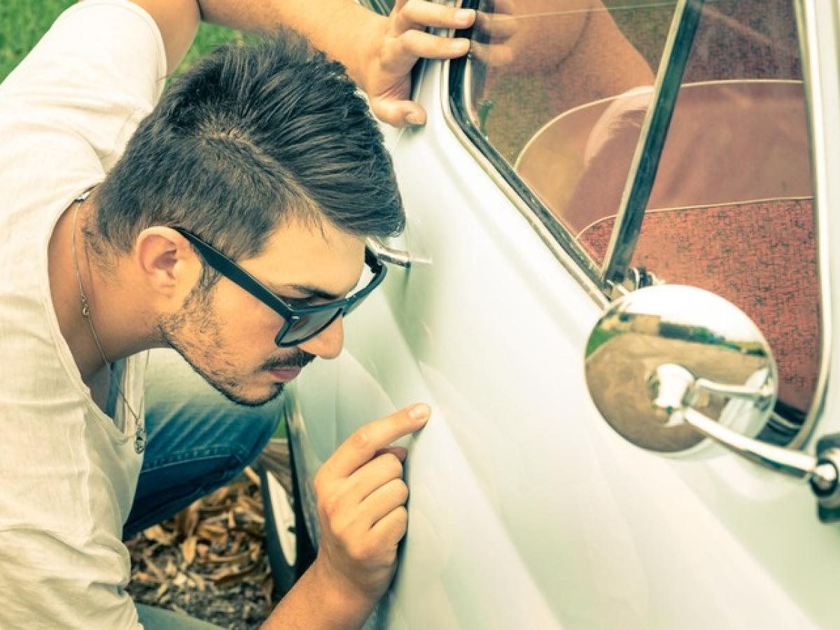 Ein Mann überprüft sein Auto auf einen Kratzer in seiner Tür