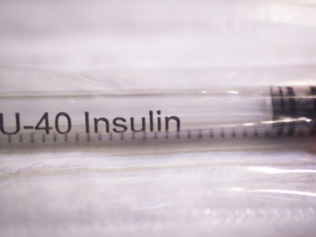 Eine Spritze mit Insulin liegt auf einer Unterlage.