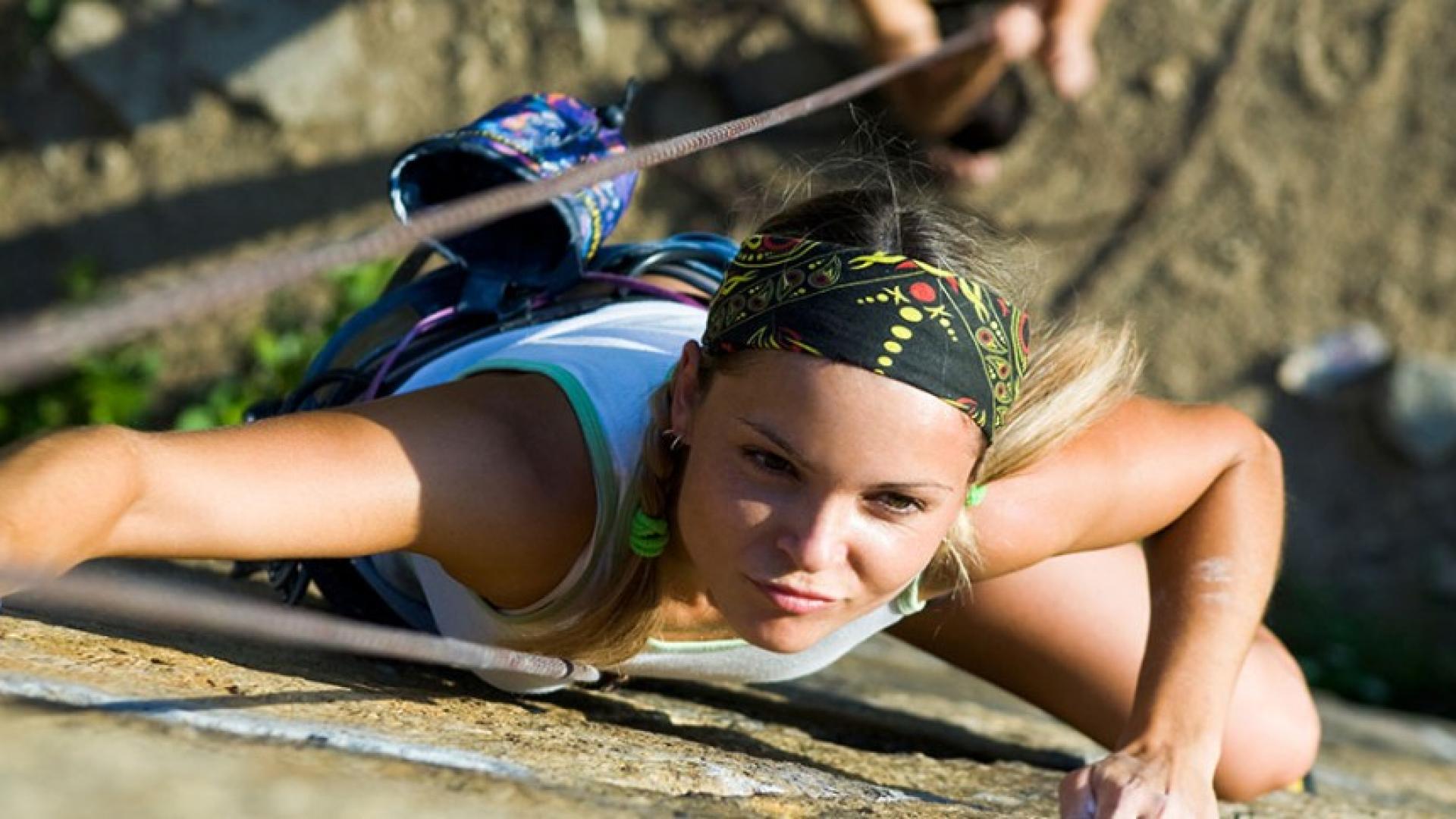 Frau klettert Kletterwand hoch.