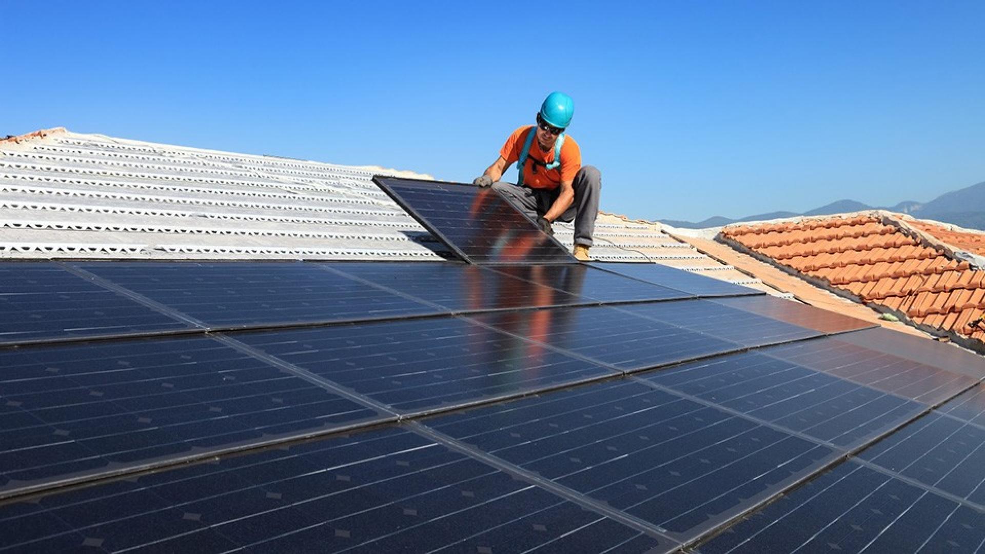 Ein Handwerker montiert Photovoltaikzellen - Symbolbild Photovoltaikversicherung