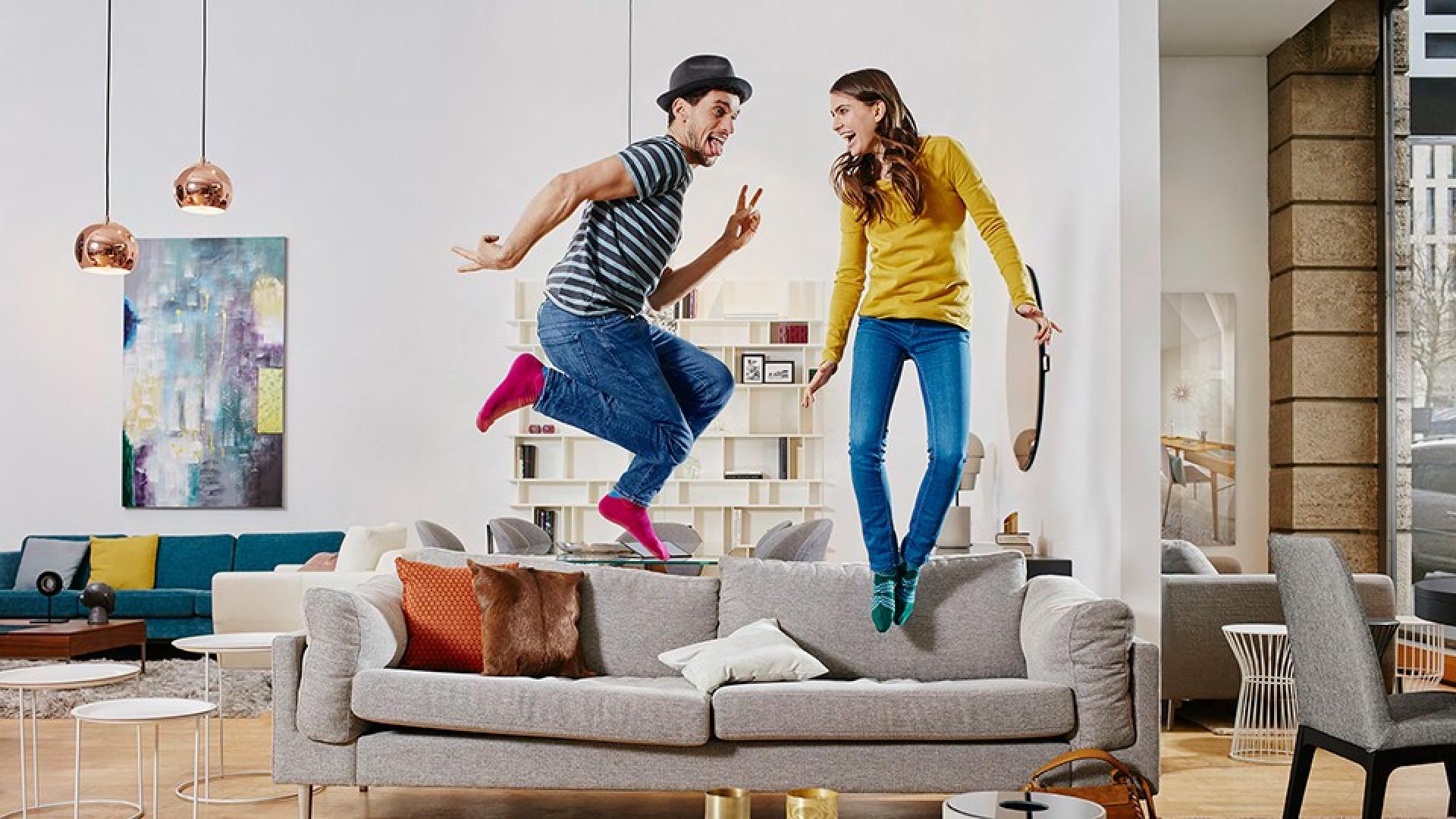 Zwei Personen springen auf einem Sofa 