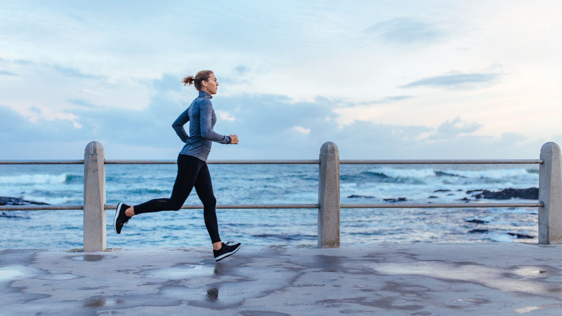 Fitness woman running on a road by the sea