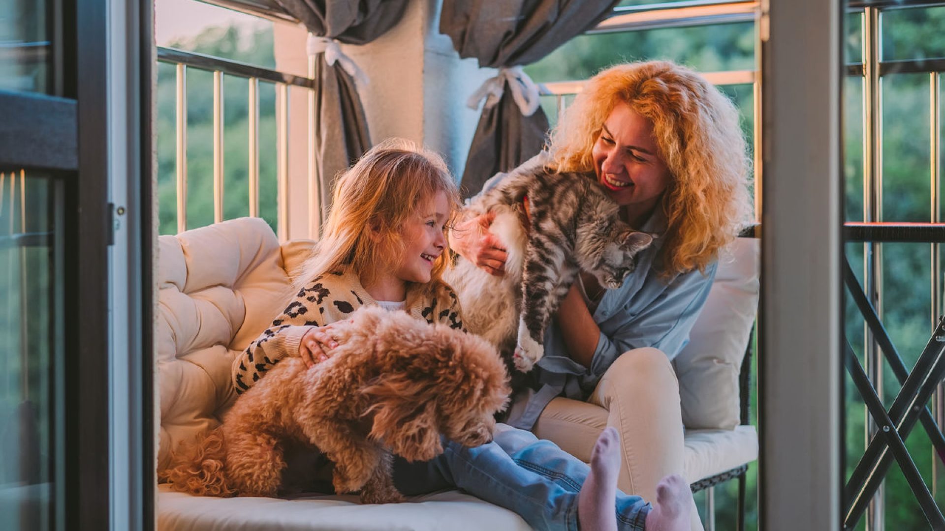 mamma che tiene in braccio un gatto e figlia che accarezza un cane