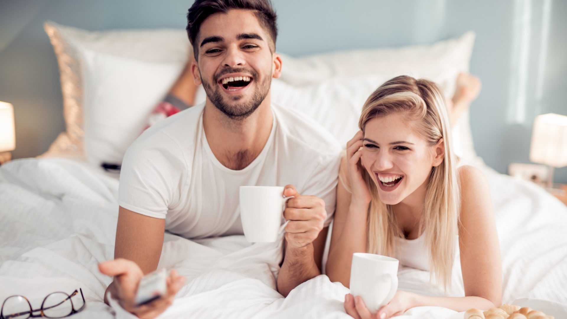 Happy man and woman having breakfast in bed.