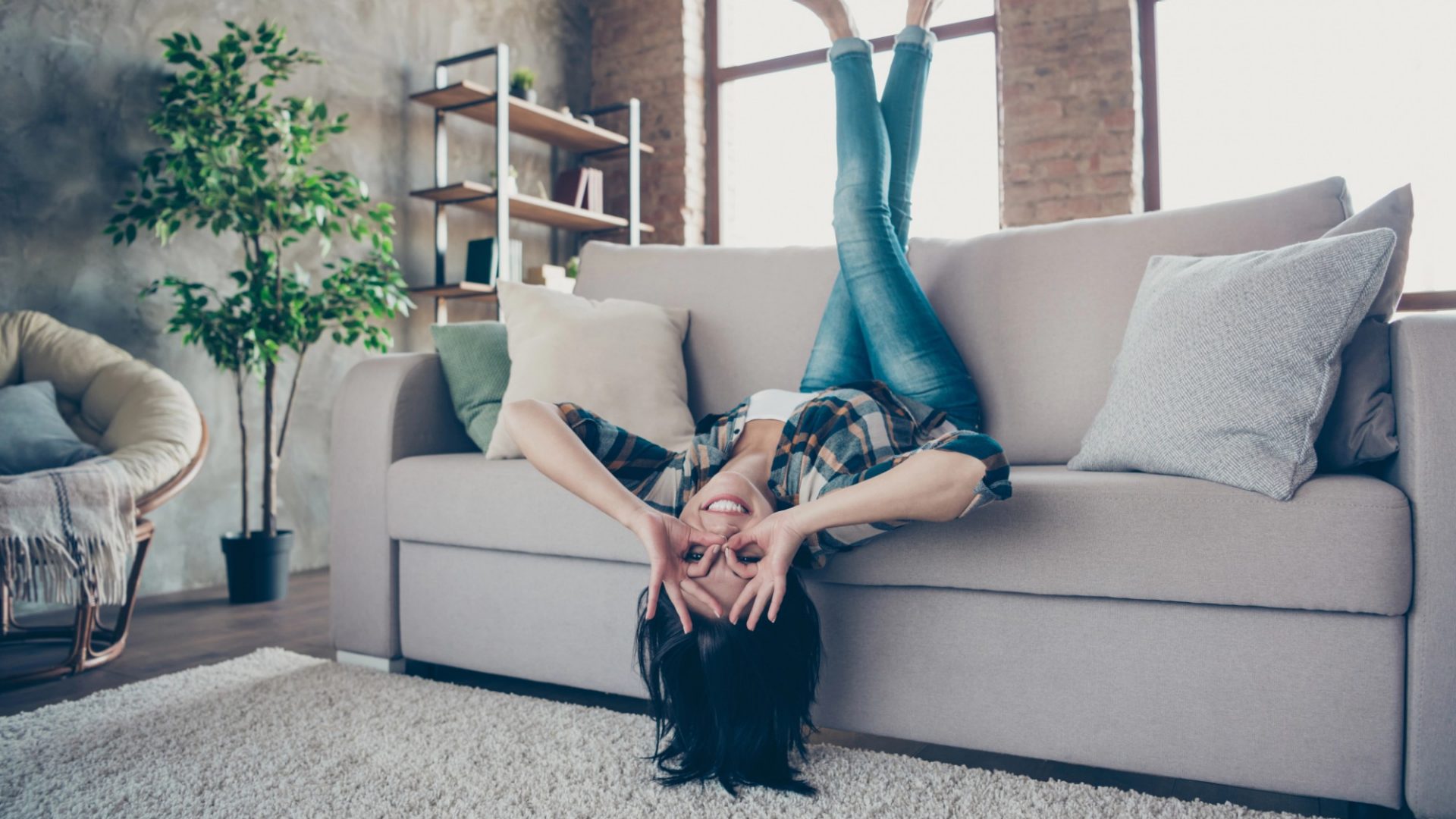 signora che gioisce sul divano con le gambe all'aria