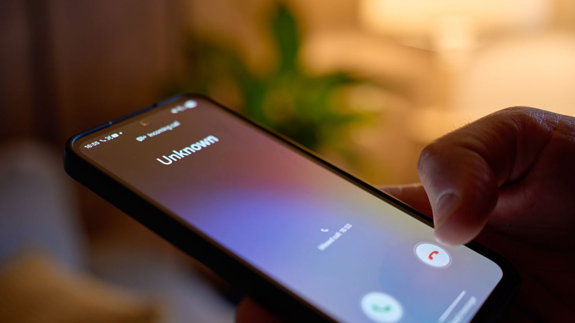 Particolare di mano che tiene un cellulare con una chiamata da sconosciuto 