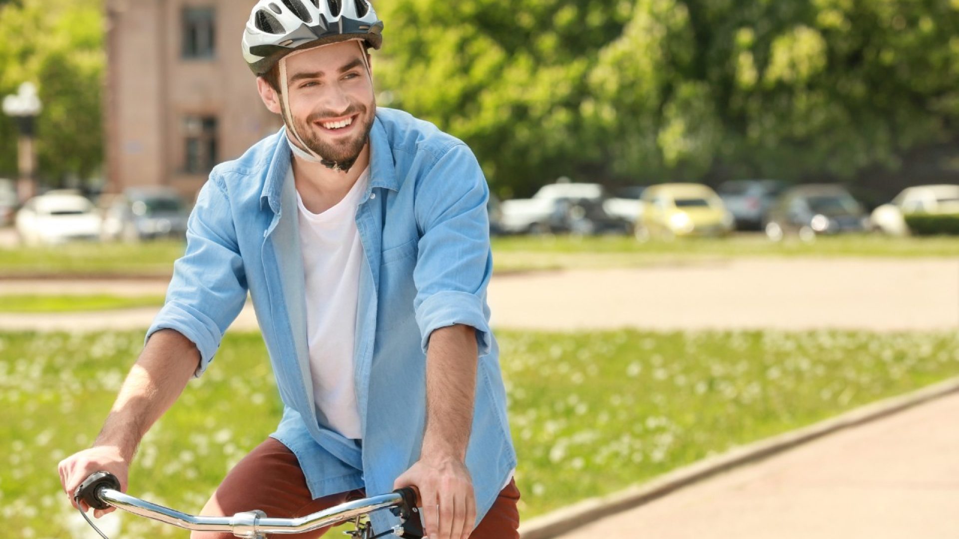 Handsome young man riding bicycle in park on sunny day