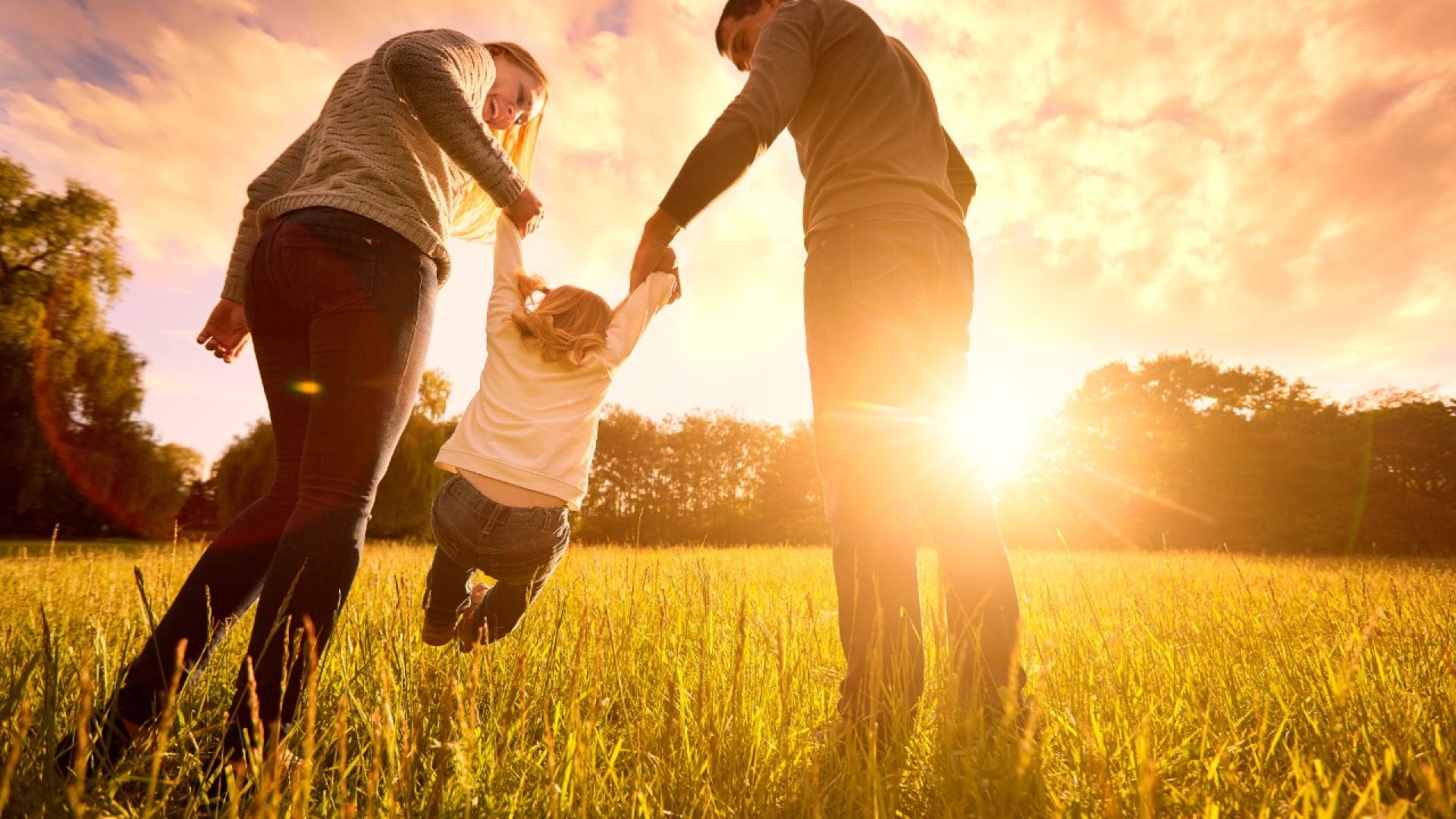 Parents hold the baby's hands.  Happy family in the park evening light. The lights of a sun. Mom, dad and baby happy walk at sunset. The concept of a happy family.