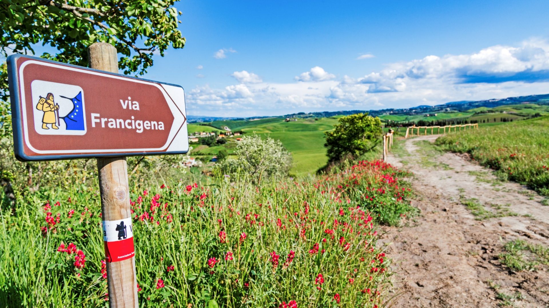 Via Francigena pilgrim path, Tuscany, Italy: road sign at beautiful Tuscany landscape background, spring scenery. Via Francigena is famous pilgrim path and popular travel hiking trail.