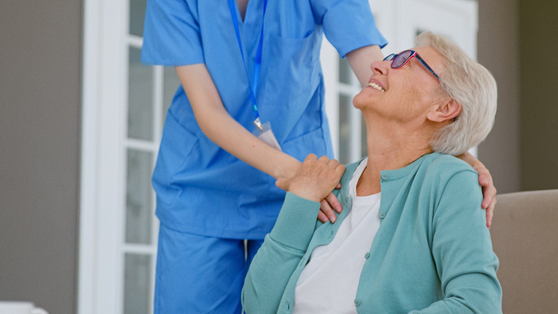 signora anziana che riceve una mano sulla spalla da una infermiera